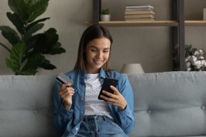 woman holding bank card and looking at mobile phone